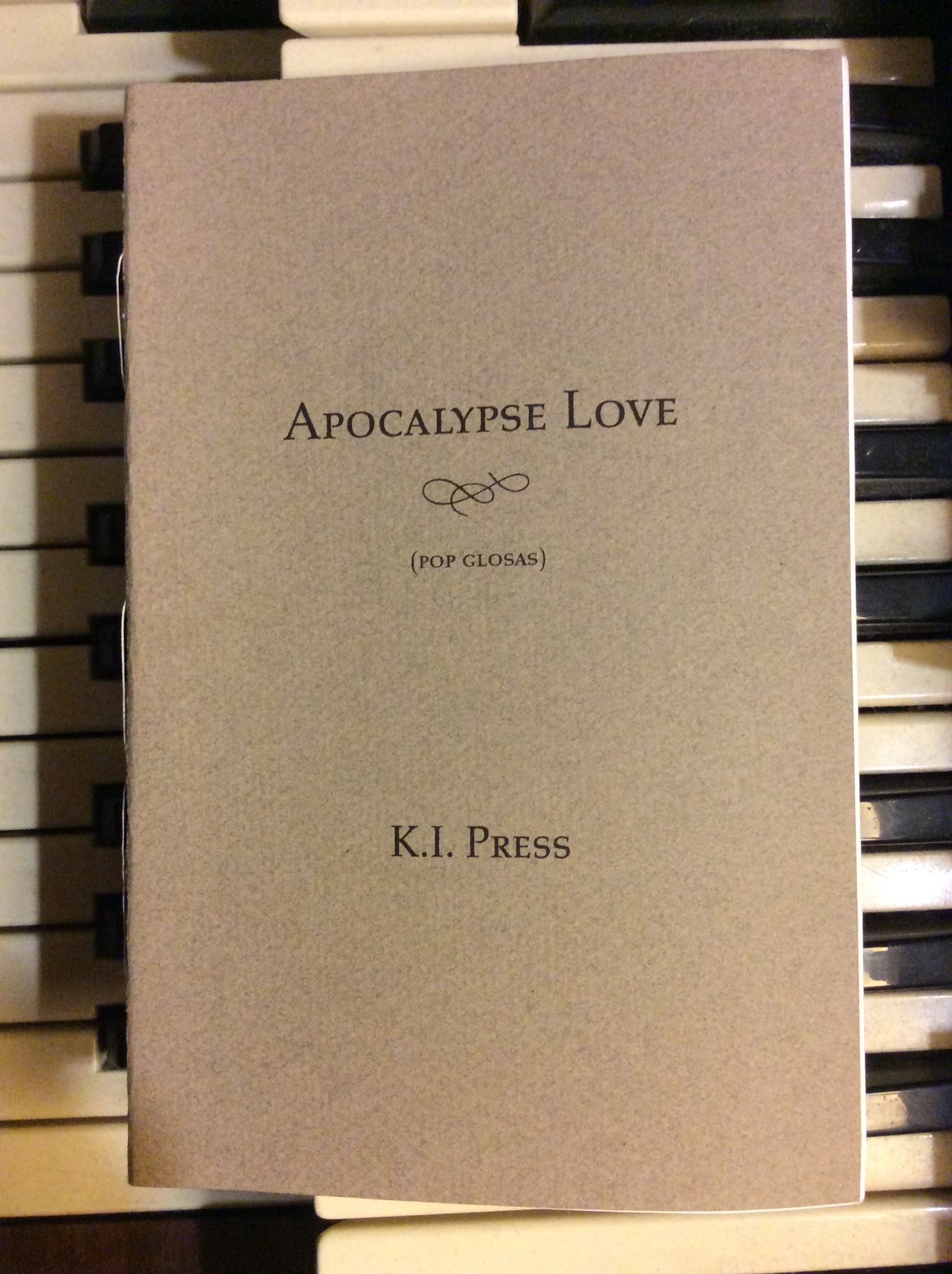 chapbook Apocalypse Love sitting on top of piano keys
