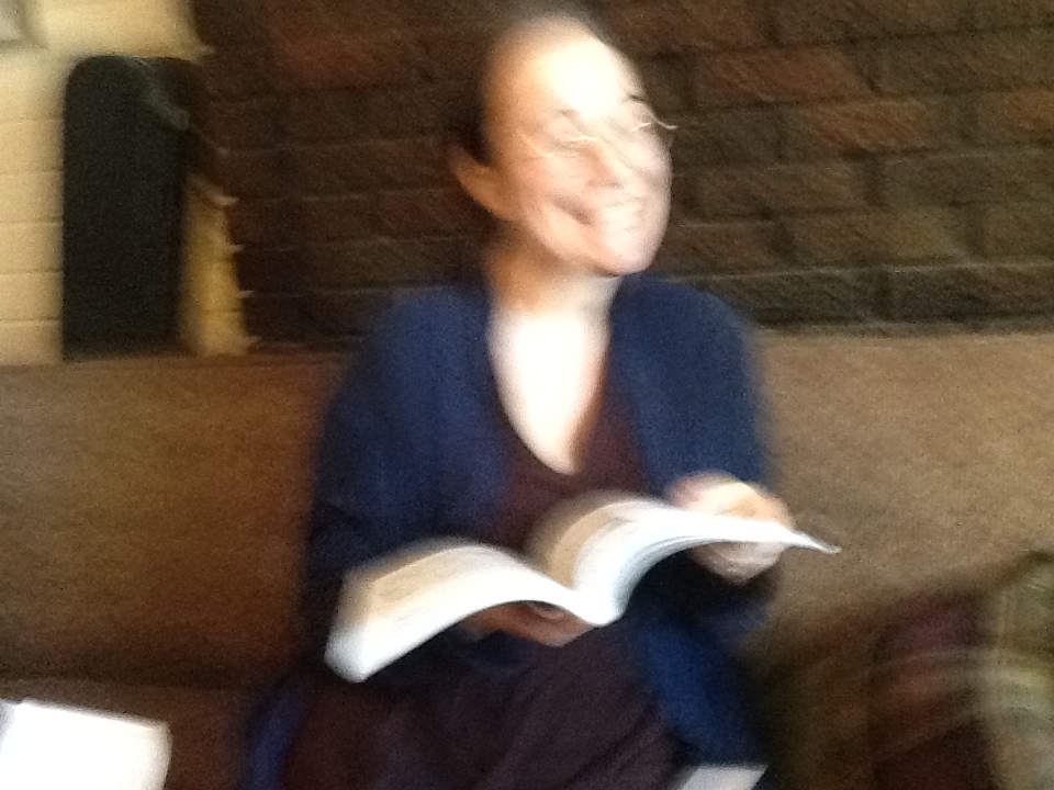 Blurry photograph of the author, spilling wide and holding an open book.
